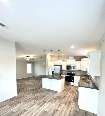 a large kitchen with stainless steel appliances kitchen island a stove a refrigerator a sink dishwasher with a dining table and chairs with wooden floor