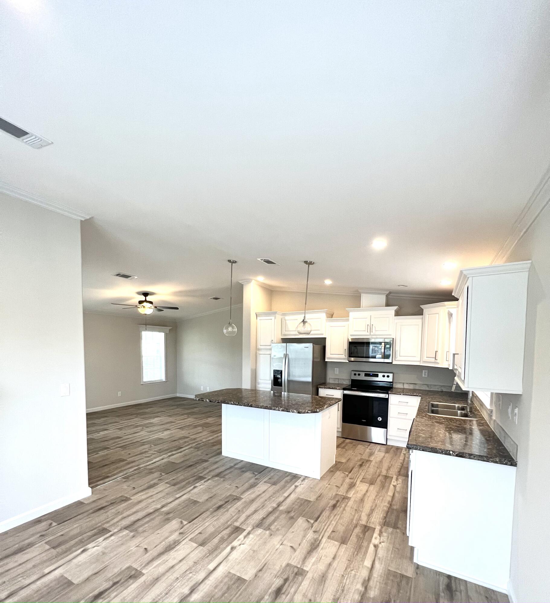 a large kitchen with stainless steel appliances kitchen island a stove a refrigerator a sink dishwasher with a dining table and chairs with wooden floor