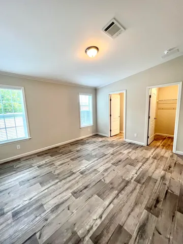 a view of empty room with wooden floor and fan