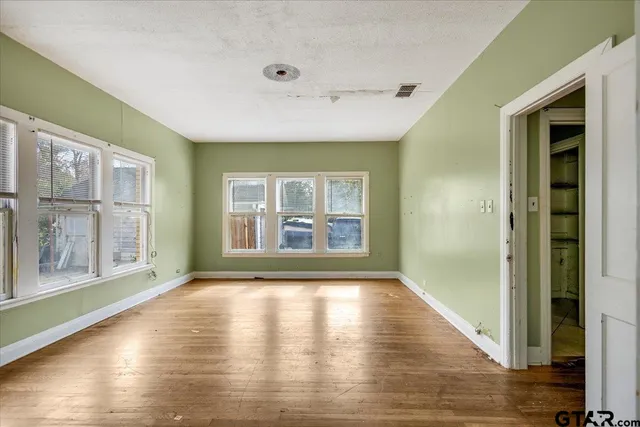 a view of an empty room with glass door and wooden floor