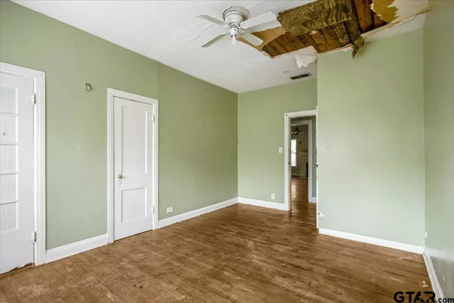 an empty room with windows and fan