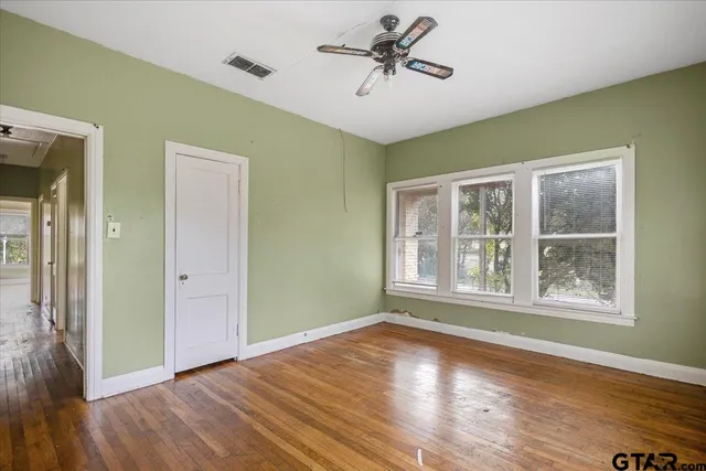 a view of empty room with wooden floor and fan