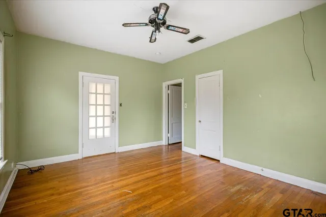 a view of an empty room with window and wooden floor