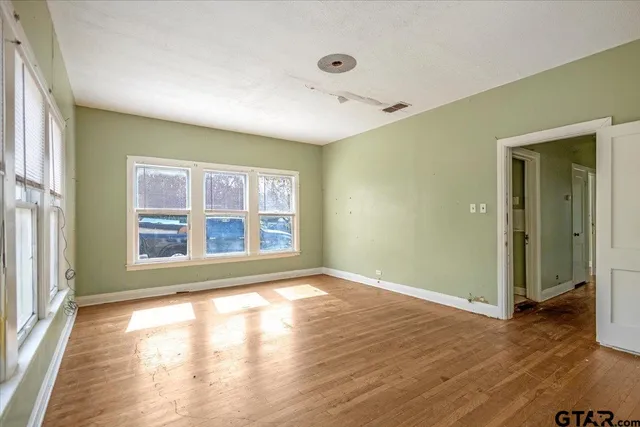 a view of an empty room with wooden floor and a window