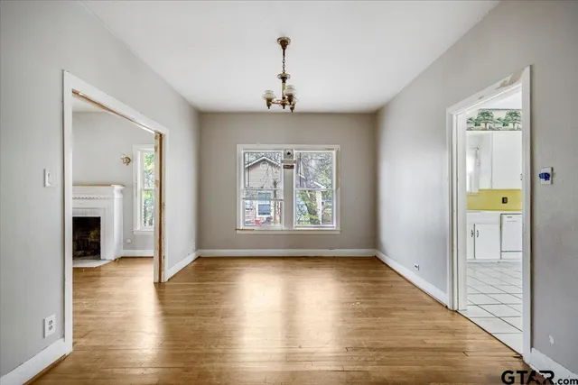 a view of an empty room with window and wooden floor