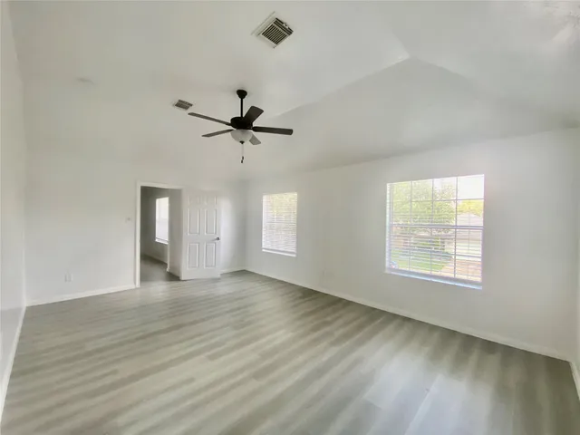 a view of an empty room with a window and wooden floor