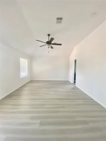 a view of a room with wooden floor and ceiling fan