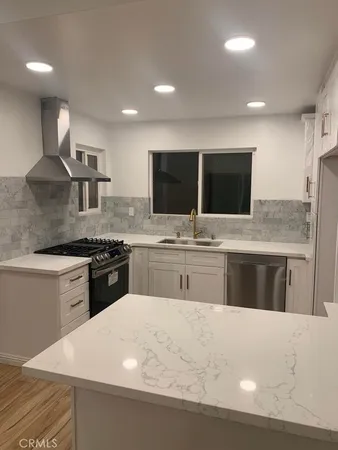 a large kitchen with stainless steel appliances kitchen island granite countertop a sink and a stove