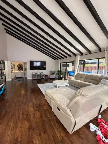 a living room with stainless steel appliances kitchen island granite countertop a sink and wooden floor