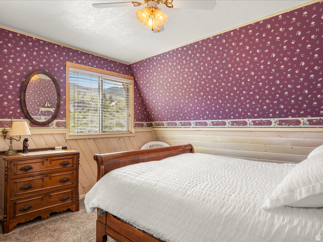 371 Lewis Loop, Unit 29 Fish Haven, ID 83287 - Photo 33 of 40 Bedroom featuring a window with integrated blinds, patterned wallpaper, natural wood paneling, and a ceiling fan with integrated lighting