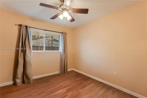 an empty room with wooden floor chandelier fan and windows