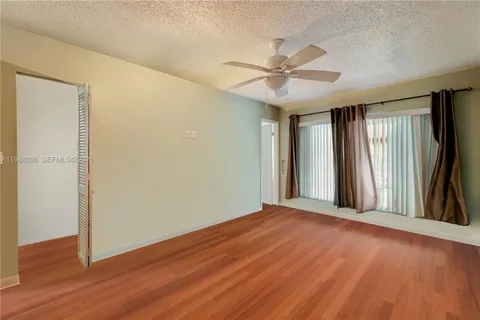 an empty room with wooden floor fan and windows