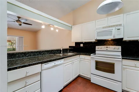 a kitchen with granite countertop white cabinets and white appliances