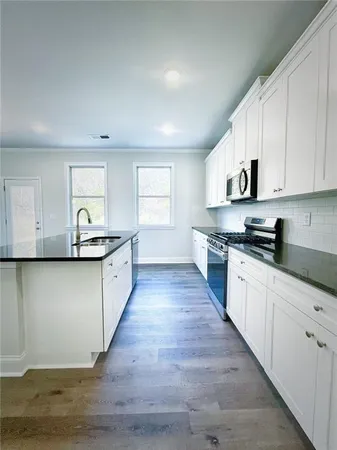a kitchen with granite countertop a sink cabinets and stainless steel appliances