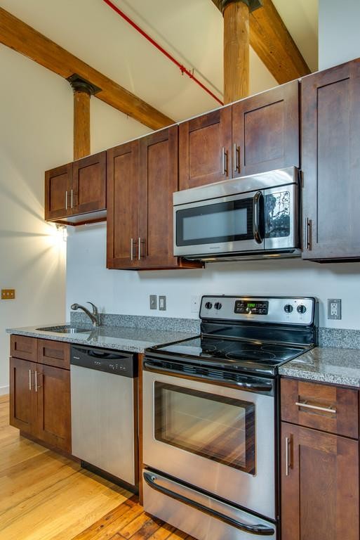 1350 Rosa L Parks Boulevard, Unit 239 Nashville, TN 37208 - Photo 9 of 23 a kitchen with stainless steel appliances granite countertop a sink a stove a microwave and wooden cabinets