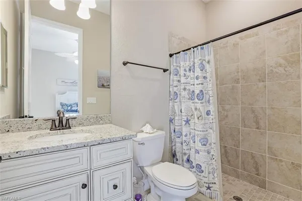 a bathroom with a granite countertop sink a toilet and shower