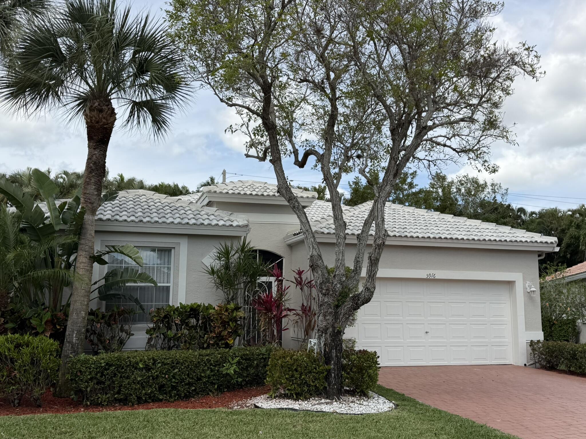 5916 Seashell Terrace Boynton Beach, FL 33437 - Photo 4 of 81 a front view of a house with a garden and trees
