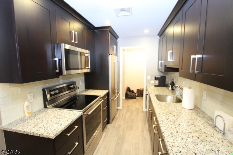 70 Harristown Road, Unit 3 Fair Lawn, NJ 07410 - Photo 5 of 20 a kitchen with stainless steel appliances granite countertop a sink stove and refrigerator