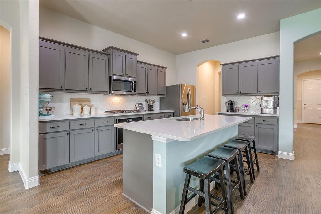 15141 Fleet Hill Road Aledo, TX 76008 - Photo 6 of 37 a kitchen with a sink a stove a refrigerator cabinets and a center island