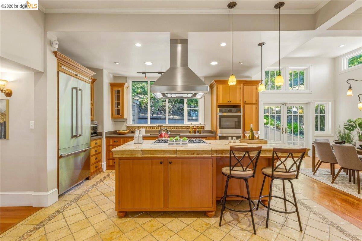 1631 La Vereda Road Berkeley, CA 94709 - Photo 8 of 42 Spacious kitchen featuring an island with counter seating, stainless steel appliances, wood cabinetry, and tile flooring