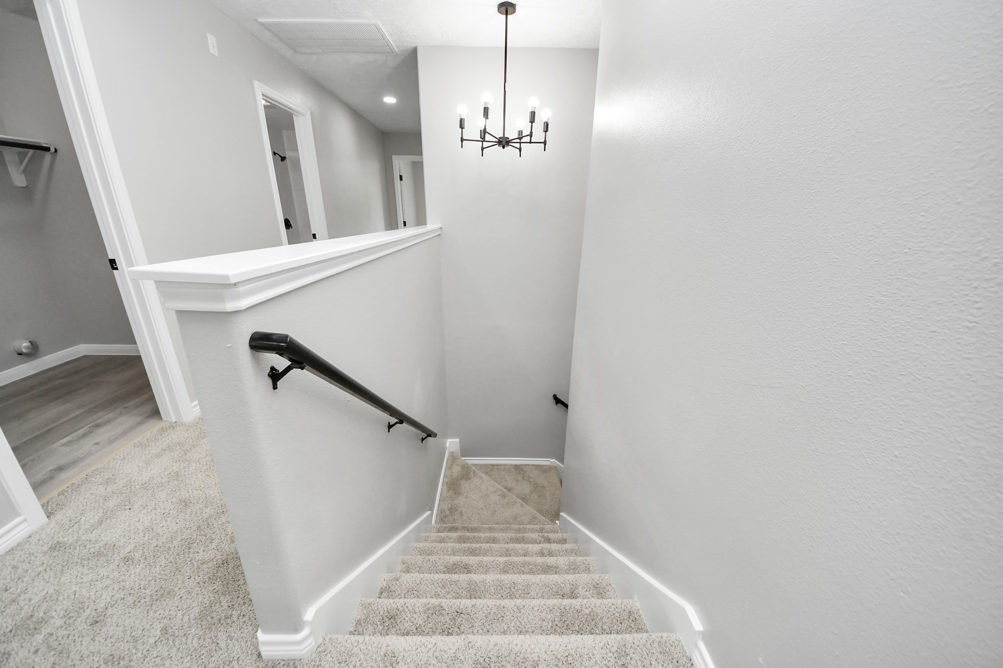 1105 East Kyle Road Clute, TX 77531 - Photo 18 of 44 The staircase leads to the upper hallway. The walls are painted in a neutral gray, and a stylish chandelier provides light.
