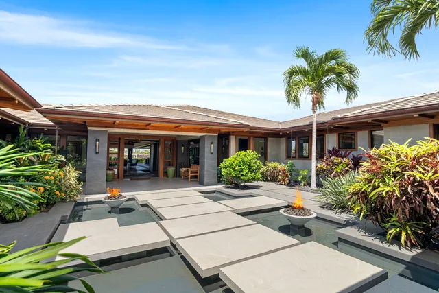 a view of a house with potted plants and a bench