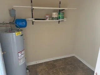 a close view of a utility room with water heater and racks on the wall