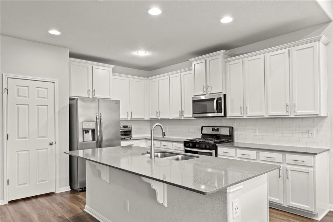 213 Munk Lane Leander, TX 78641 - Photo 10 of 40 a kitchen with stainless steel appliances granite countertop a sink stove refrigerator and cabinets