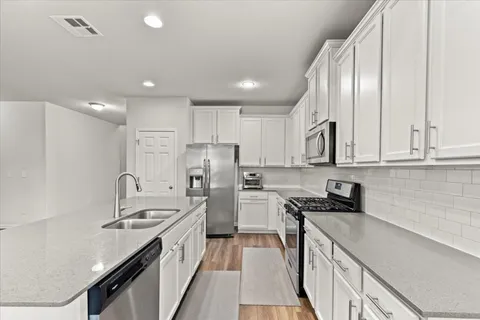 a kitchen with stainless steel appliances granite countertop a sink stove refrigerator and cabinets