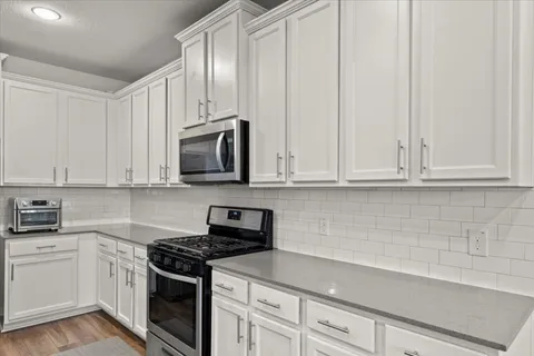 a kitchen with stainless steel appliances granite countertop a sink a stove and a refrigerator