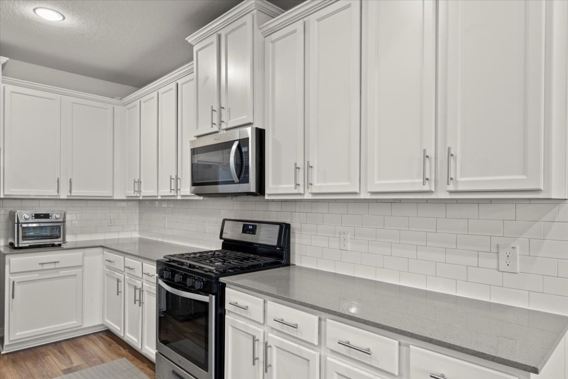 213 Munk Lane Leander, TX 78641 - Photo 13 of 40 a kitchen with stainless steel appliances granite countertop white cabinets and a stove