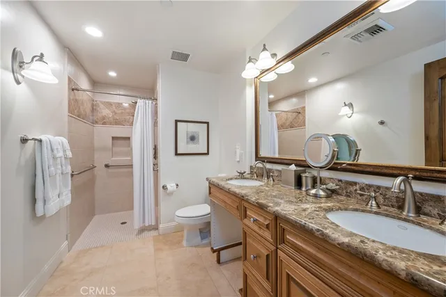 a bathroom with a granite countertop double vanity sink a mirror and a toilet