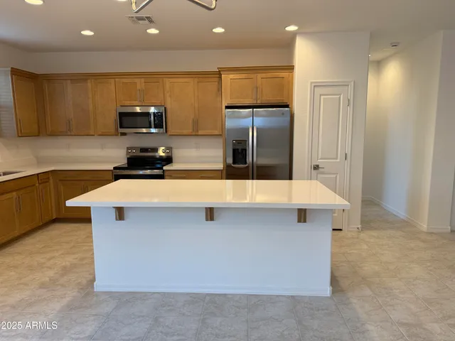 a kitchen with stainless steel appliances a sink a stove a microwave a refrigerator a counter top and cabinets