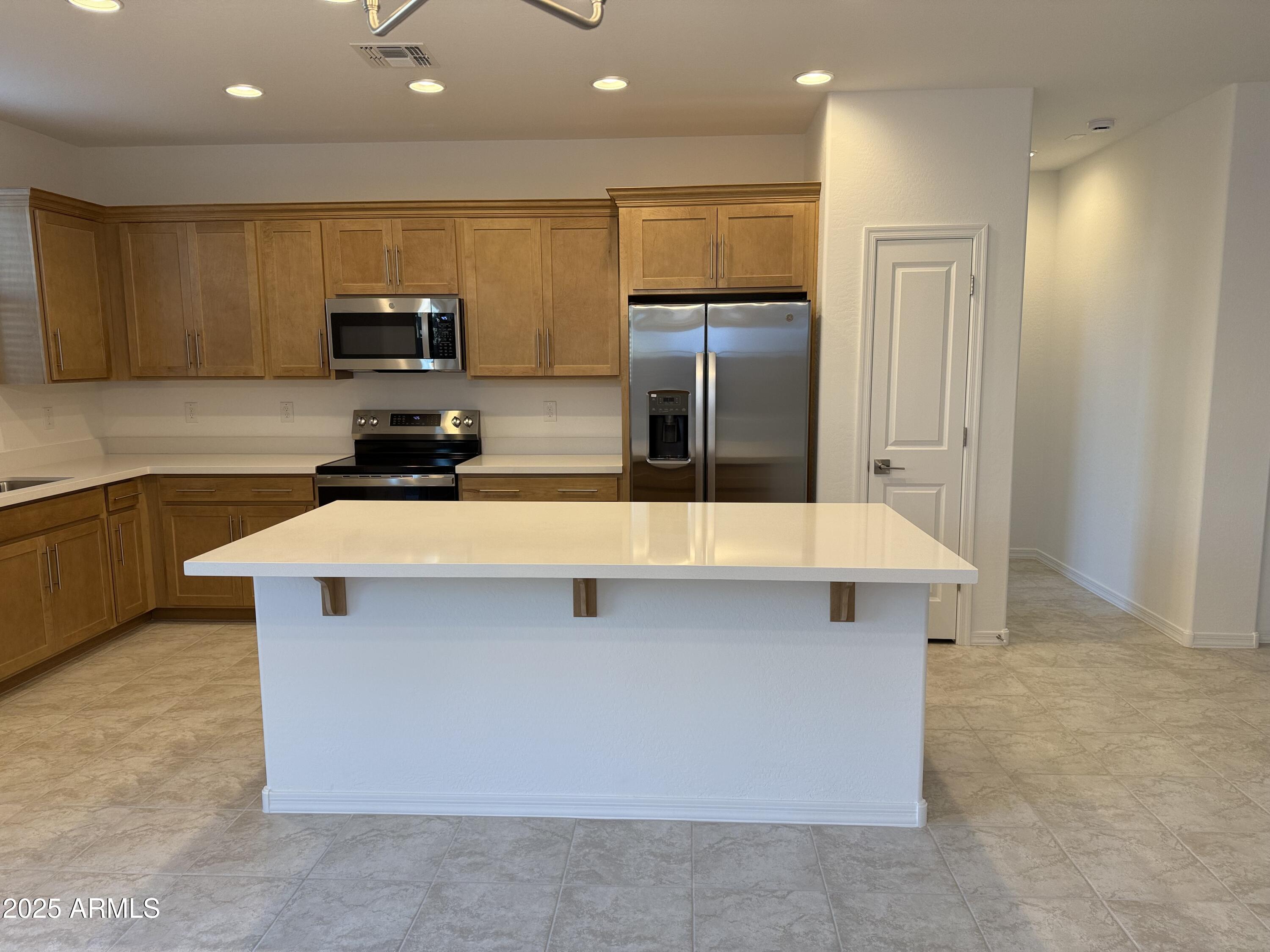 9960 West Mitchell Avenue Avondale, AZ 85392 - Photo 3 of 25 a kitchen with stainless steel appliances a sink a stove a microwave a refrigerator a counter top and cabinets