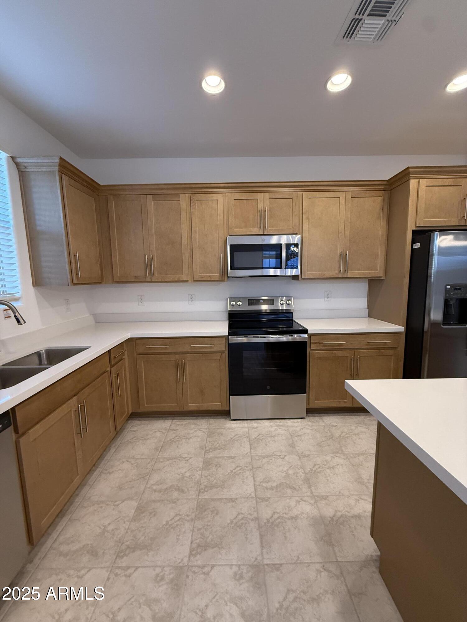9960 West Mitchell Avenue Avondale, AZ 85392 - Photo 8 of 25 a kitchen with stainless steel appliances a sink a stove top oven a counter space and cabinets