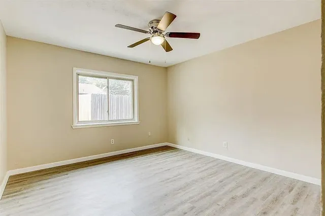 an empty room with a window and a ceiling fan