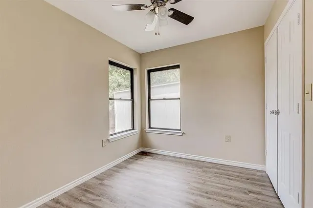 an empty room with windows and ceiling fan