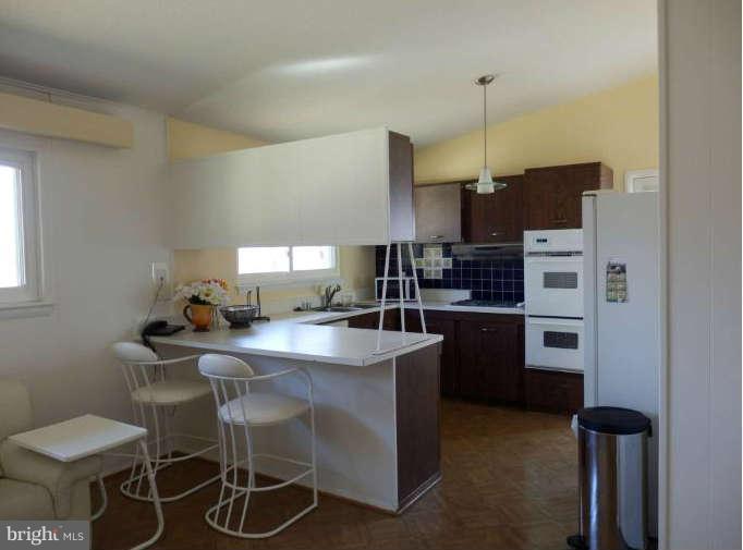 8250 Brattle Road Baltimore, MD 21208 - Photo 9 of 17 a kitchen with a dining table chairs and a refrigerator