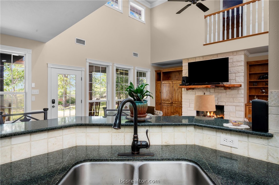 6400 Koppe Bridge Road College Station, TX 77845 - Photo 23 of 47 Kitchen with dark stone countertops, a fireplace, ceiling fan, and a high ceiling