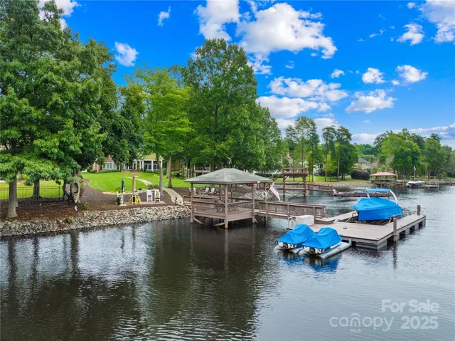 a view of a lake with table and chairs and potted plants and big trees