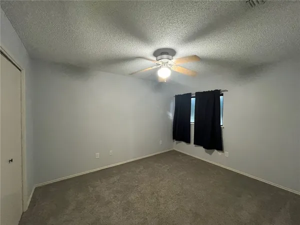 an empty room with chandelier fan and windows
