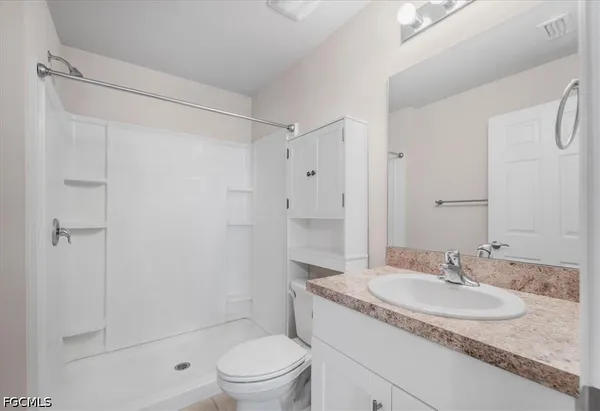 a bathroom with a granite countertop sink a toilet and shower