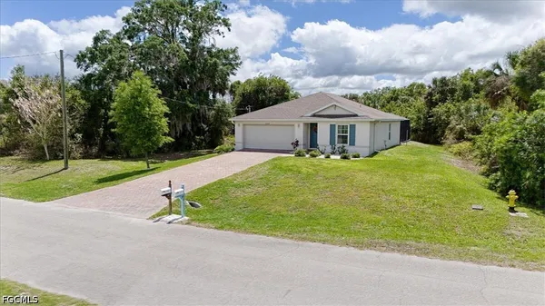a view of a house with a yard and large trees
