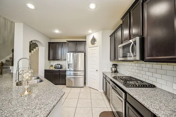 a kitchen with stainless steel appliances granite countertop a sink stove and refrigerator