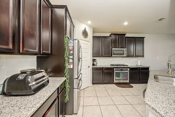 a kitchen with granite countertop a cabinets and chairs