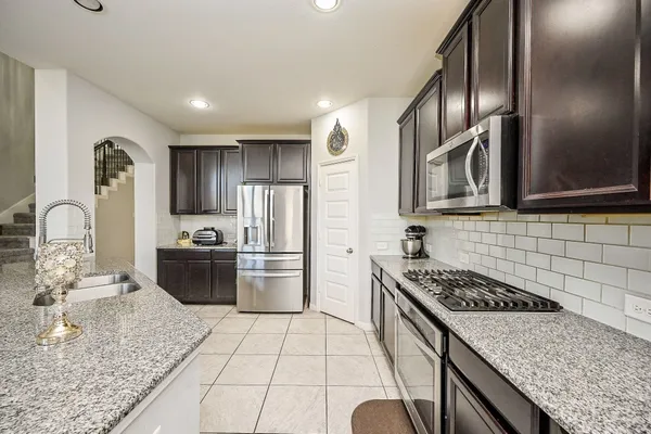 a kitchen with stainless steel appliances granite countertop a stove a sink a microwave a dining table and chairs