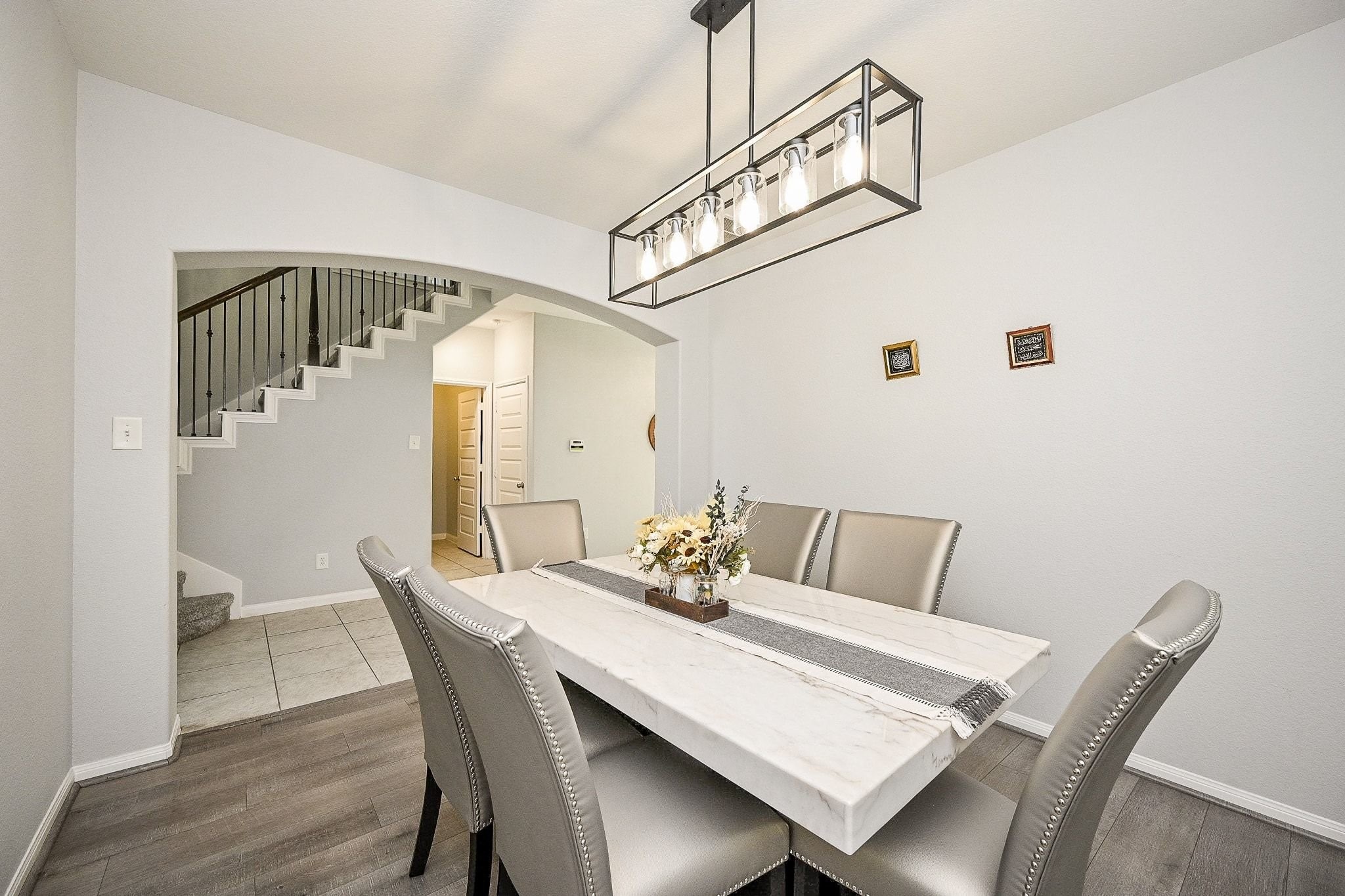 7042 Sliding Rock Circle Spring, TX 77379 - Photo 7 of 44 This elegant dining room features a modern chandelier, a sleek marble table, and plush seating for six. The open archway leads to a stylish staircase, enhancing the home's sophisticated charm.