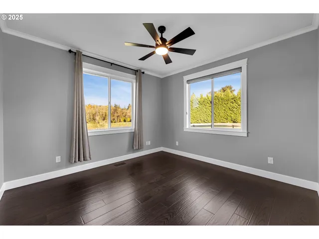 an empty room with wooden floor ceiling fan and windows