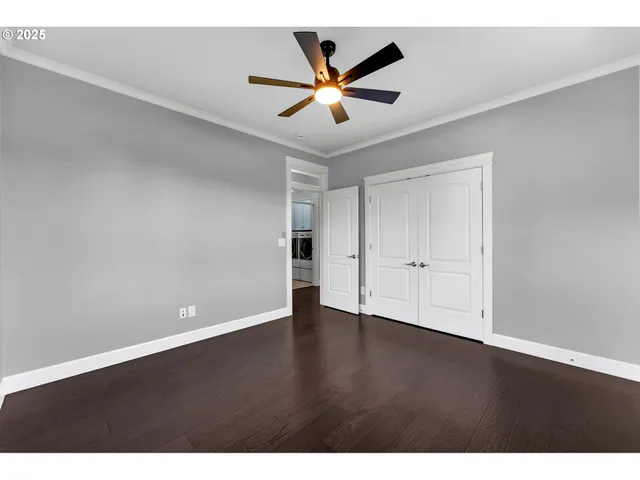 an empty room with wooden floor and ceiling fan