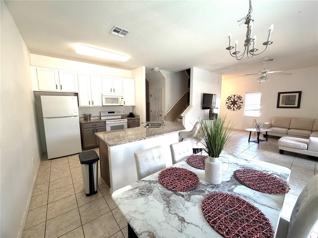 4573 Ada Lane Kissimmee, FL 34746 - Photo 6 of 37 a living room with furniture a chandelier and a dining table with kitchen view